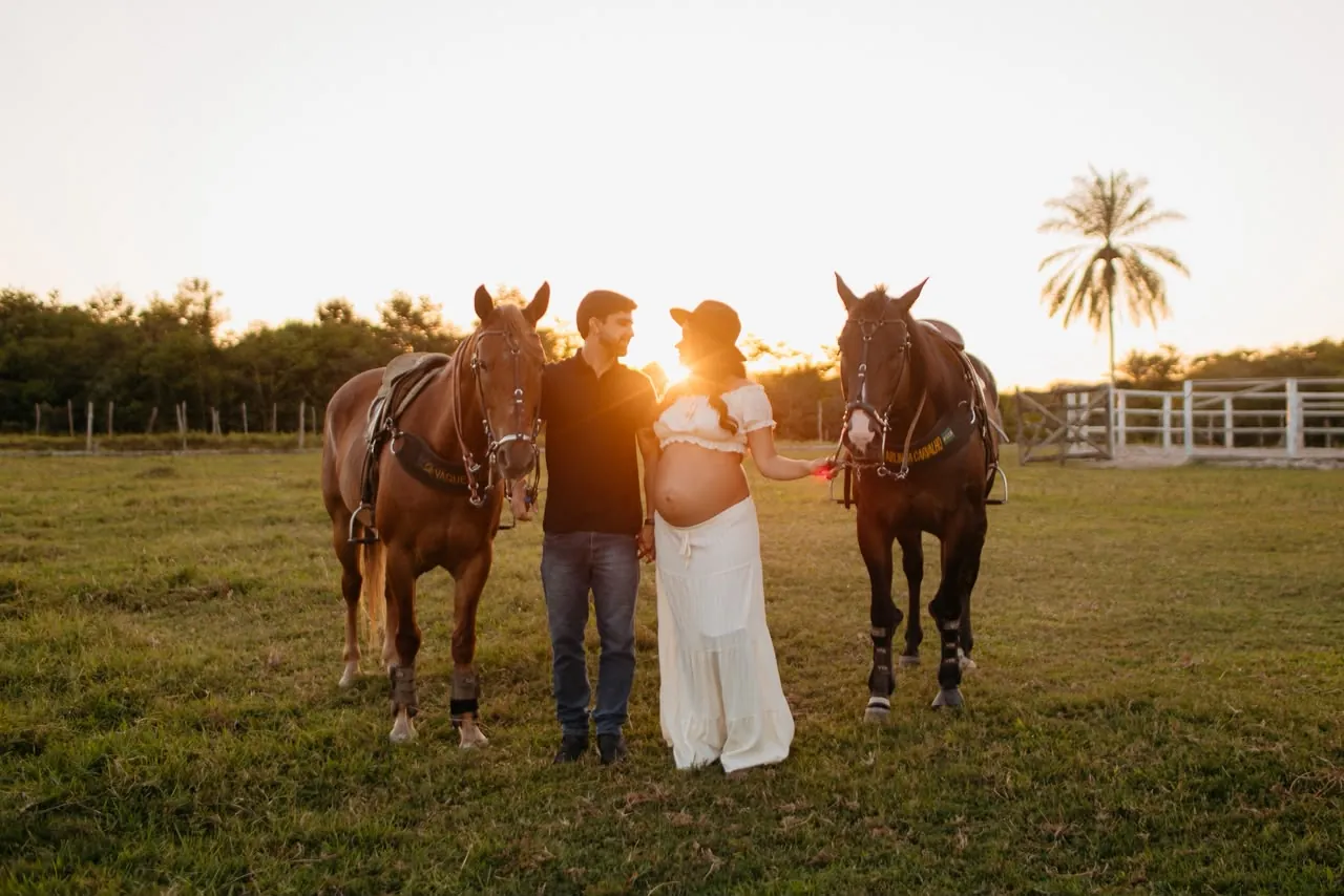 Casal com dois cavalos ao pôr do sol, ensaio de gestante