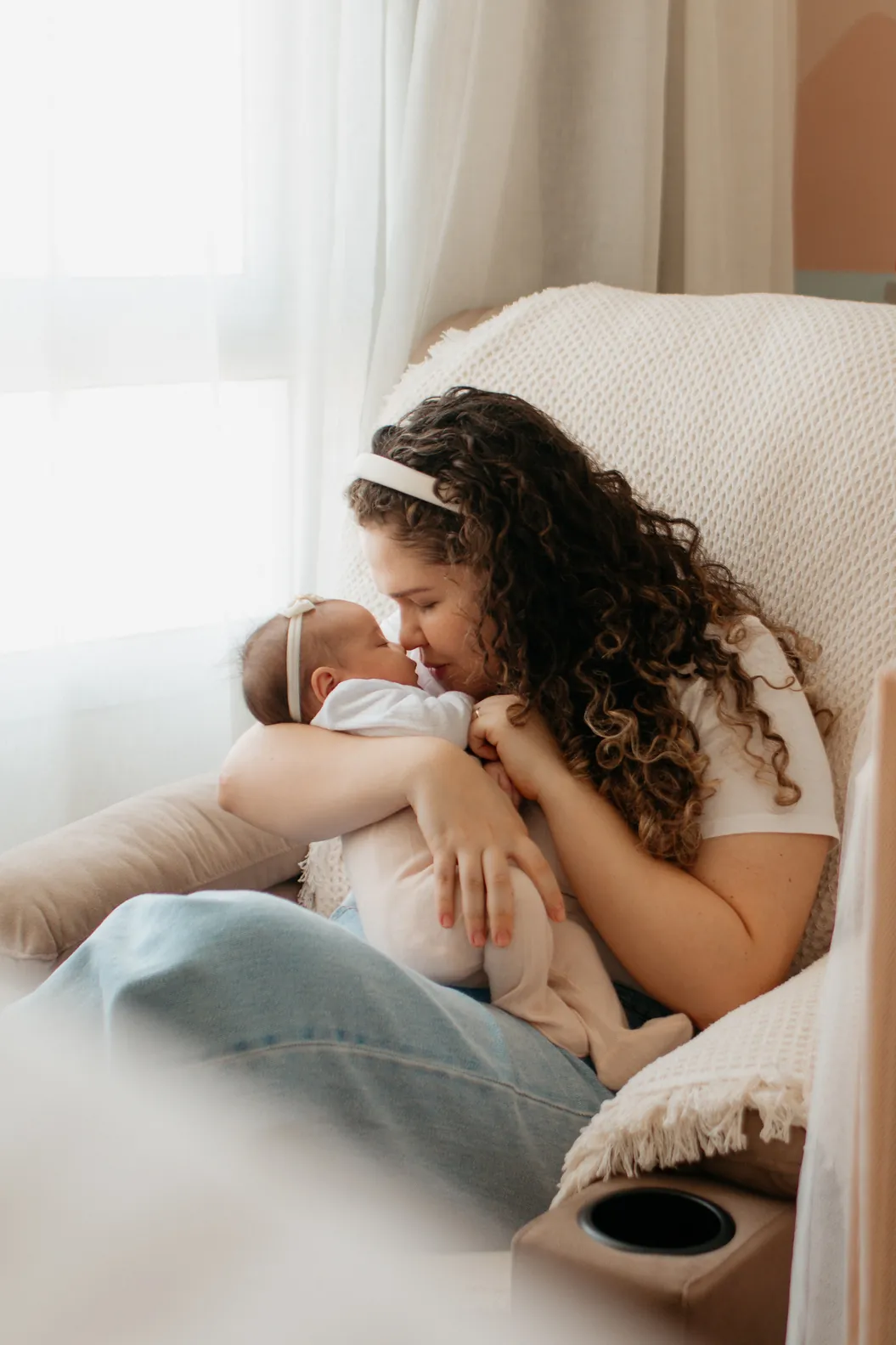 Mãe com o bebê no colo, perto da janela