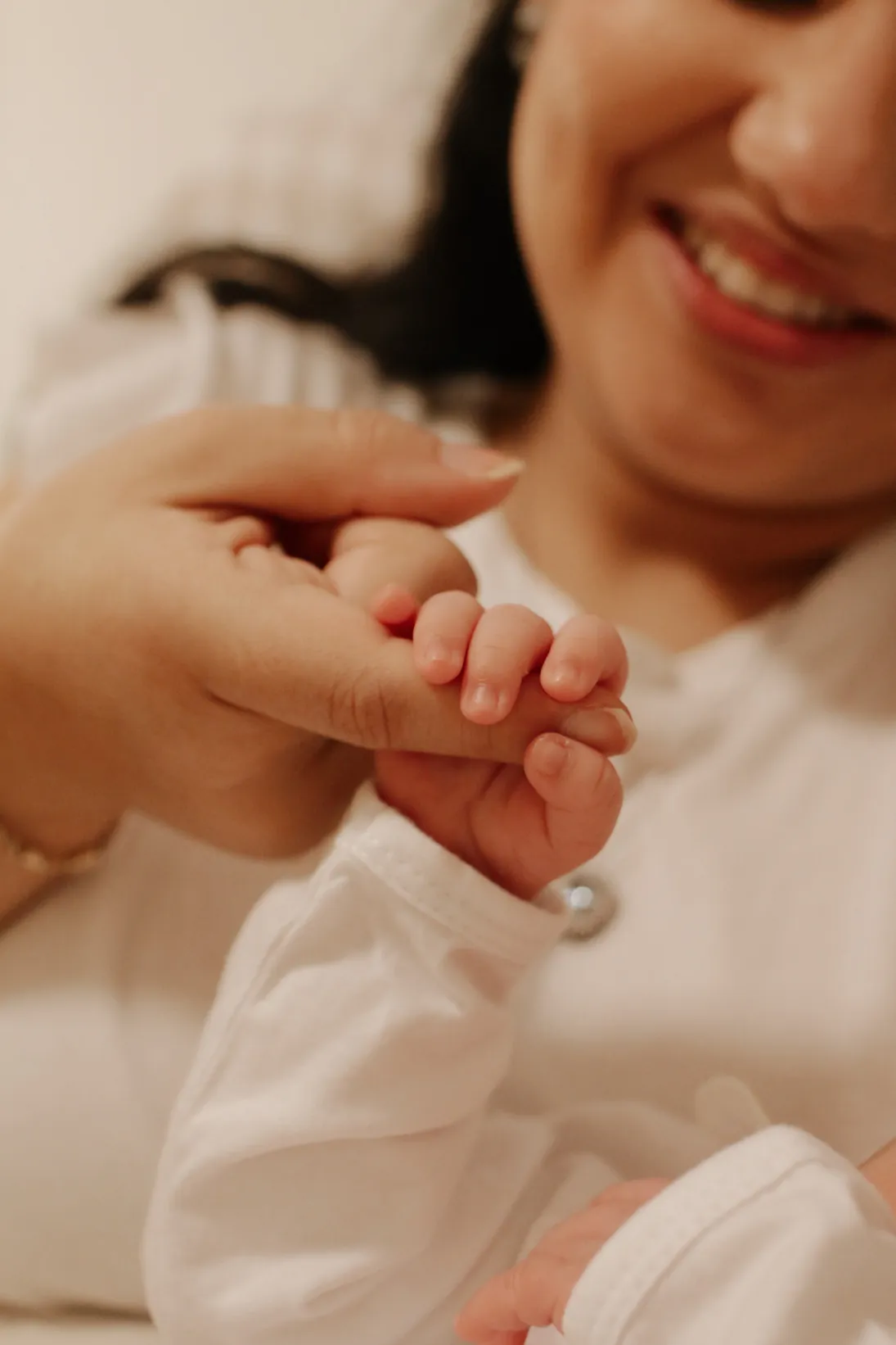 Mão da mãe segurando a mãozinha do bebê
