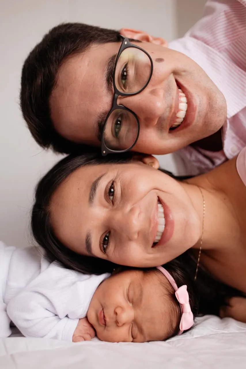 Pais e recém-nascida sorrindo, rosto com rosto
